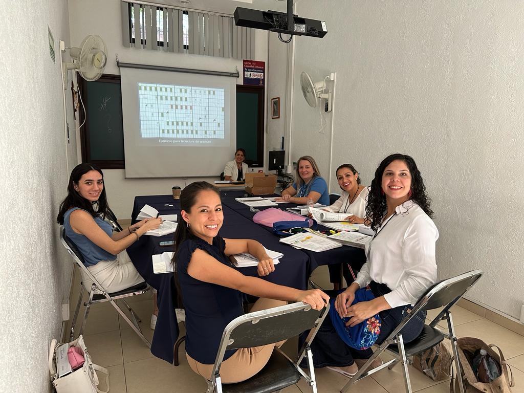 Participantes do programa educativo trabalhando em equipe com seus materiais de estudo.